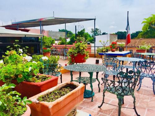 eine Terrasse mit Tischen, Stühlen und Topfpflanzen in der Unterkunft Hotel Cazomalli Oaxaca in Oaxaca de Juárez