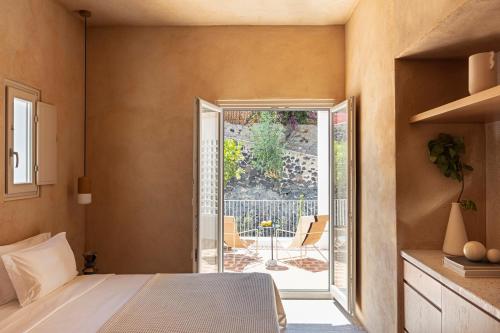 a bedroom with a bed and an open door to a patio at Ethos Vegan Suites in Fira