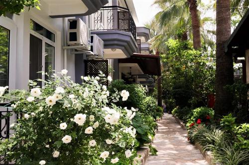 een tuin met witte bloemen voor een gebouw bij Canada Hotel & Bungalows in Cıralı