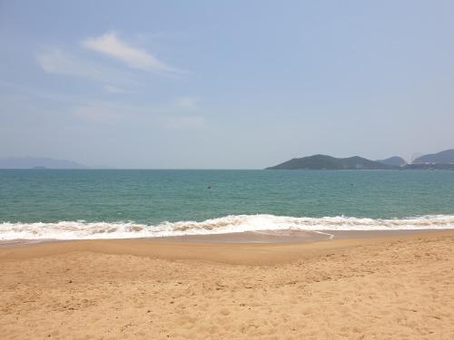 una spiaggia sabbiosa con l'oceano sullo sfondo di VANDA Hotel Nha Trang a Nha Trang