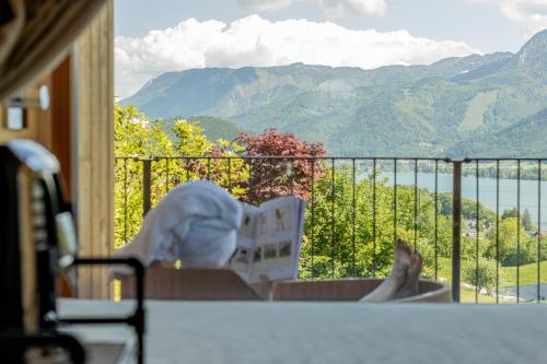 a person laying on a balcony looking out at the mountains at Balthasar Volcano Apartments - Adults only in St. Wolfgang