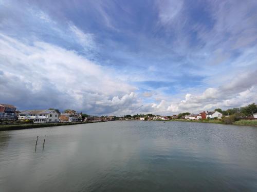 Une grande masse d'eau avec des maisons en arrière-plan dans l'établissement Frankland - Emsworth Harbour 3 Bedroom House, à Emsworth