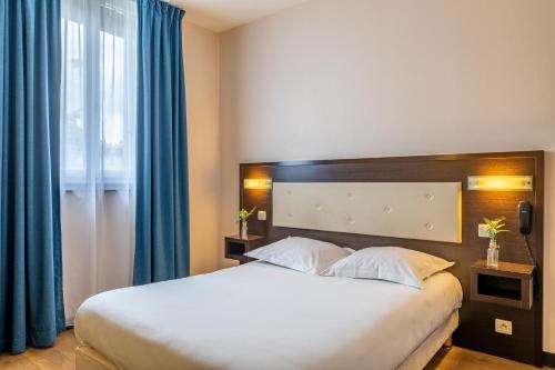 a bedroom with a large bed with blue curtains at Hôtel Le Florin in Rennes