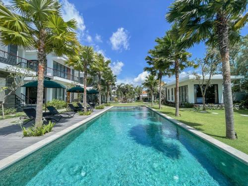 a swimming pool with palm trees in front of a building at The Valerian Villa Ubud in Ubud