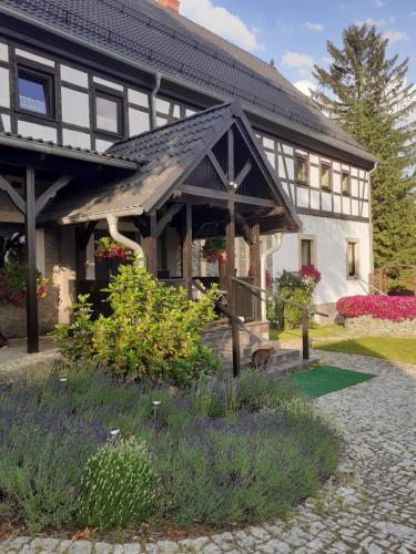 a house with a porch and flowers in front of it at Agroturystyka Łysa Góra in Jelenia Góra