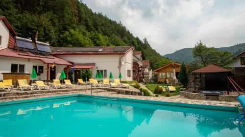 ein Resortpool mit Stühlen und Bergen im Hintergrund in der Unterkunft Pensiunea Alpin in Păltiniş