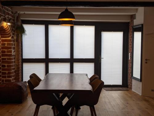 comedor con mesa, sillas y ventanas en BacksteinFlair - LüneMitte, en Lüneburg