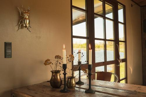 een kaars op een houten tafel met een raam bij Krusmølle Glamping in Aabenraa