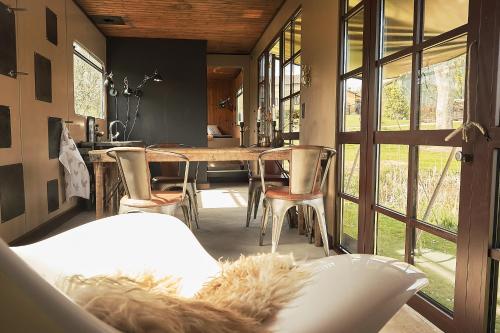 een eetkamer met een tafel, stoelen en ramen bij Krusmølle Glamping in Aabenraa