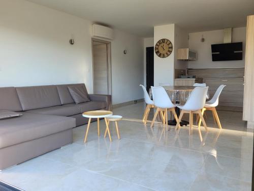 uma sala de estar com um sofá, uma mesa e cadeiras em Appartement neuf 3 chambres vue mer Propriano em Propriano