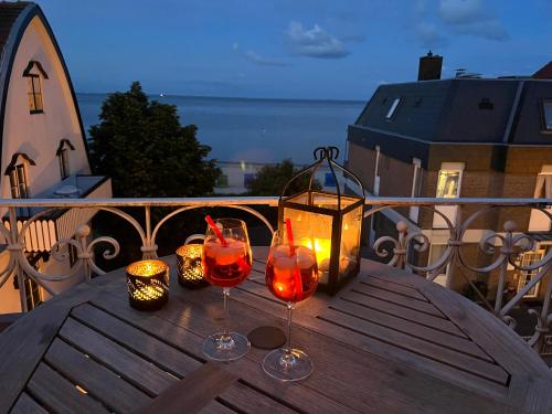 - une table avec 2 verres à vin et une lanterne sur le balcon dans l'établissement Sandwallkoje, à Wyk auf Föhr