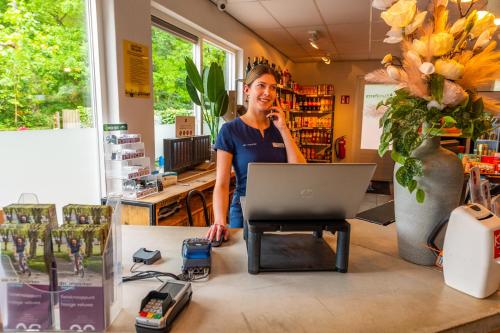 une femme qui parle sur un téléphone à un bureau avec un ordinateur portable dans l'établissement EuroParcs De Hooge Veluwe, à Arnhem