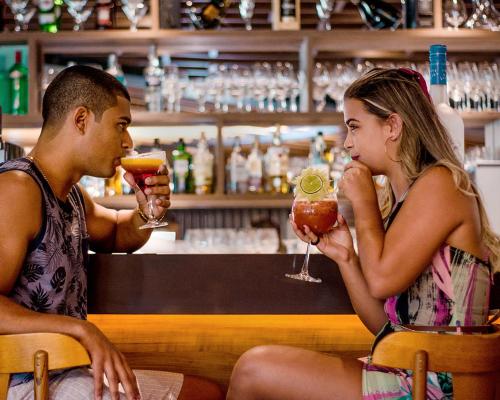 un homme et une femme assis dans un bar avec des boissons dans l'établissement Paradiso Corporate, à Cabo Frio