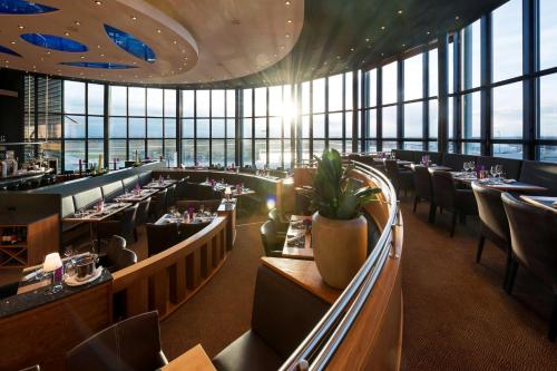 a restaurant with tables and chairs and windows at ATLANTIC Hotel Airport in Bremen