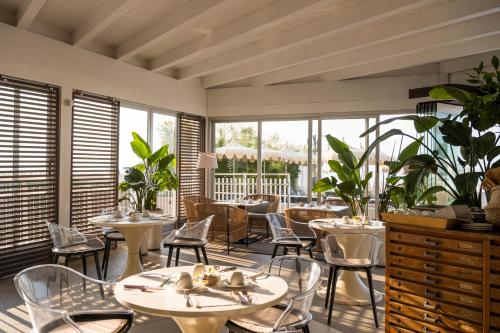 um restaurante com mesas, cadeiras e janelas em Hotel Delle Nazioni em Lido di Jesolo