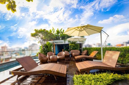 um pátio com uma mesa, cadeiras e um guarda-sol em Cochin Sang Hotel em Cidade de Ho Chi Minh