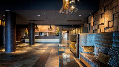 een lobby van een hotel met een bank en een bar bij Strandhotel Golfzang in Egmond aan Zee