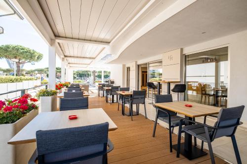 un restaurante con mesas, sillas y flores en Hotel Mare, en Lignano Sabbiadoro