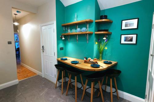 a kitchen with a blue wall with a table and stools at Tastefully Decorated 1-Bed with Free Parking - At Hem in Winchester