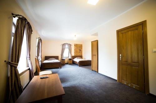 a living room with a room with two beds and a table at Hotel Stary Młyn in Suchedniów