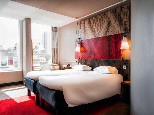 una camera d'albergo con due letti e un tappeto rosso di Ibis Den Haag City Centre a L'Aia