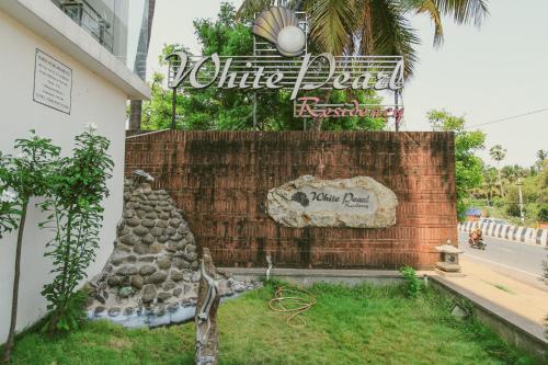 um sinal para um hotel com uma parede de pedra em White Pearl Residency em Pondicherry