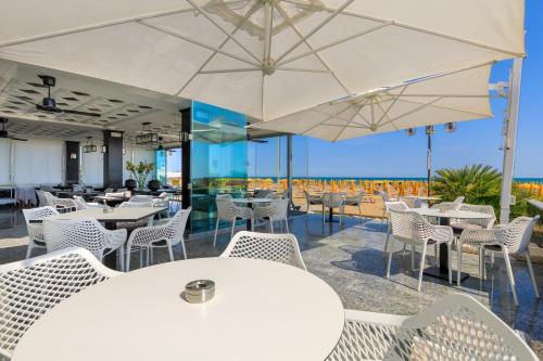 a restaurant with white chairs and tables and umbrellas at Hotel Gritti in Lido di Jesolo