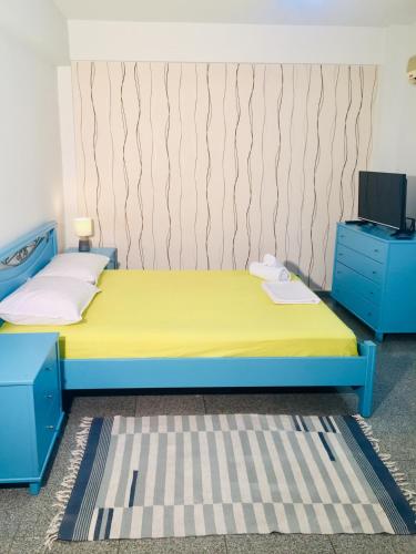 una camera con letto blu e giallo e TV di Plouto IsimeriaHomz a Salonicco