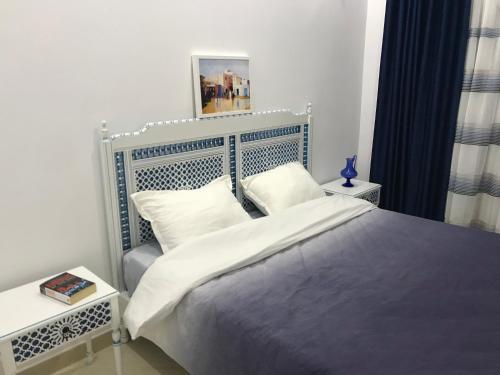 a bedroom with a large bed with a blue headboard at Cosy Appart - Central & Near main interest points in La Marsa