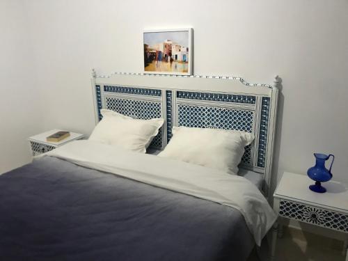 a bed with a blue headboard and two white pillows at Cosy Appart - Central & Near main interest points in La Marsa