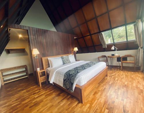 a bedroom with a large bed and a wooden floor at Bukit Tiga Lima Boutique Hotel in Sajang