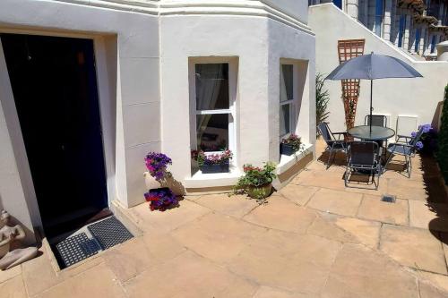 un patio con mesa, sillas y sombrilla en Beautifully appointed, period seaside apartment, en Folkestone