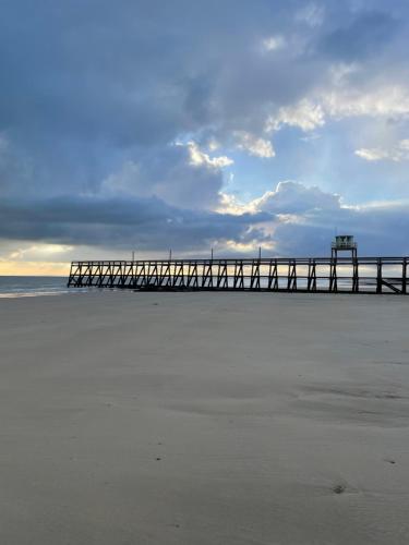 een pier op het strand met een bewolkte hemel bij Beau Rivage Hôtel-Restaurant in Luc-sur-Mer