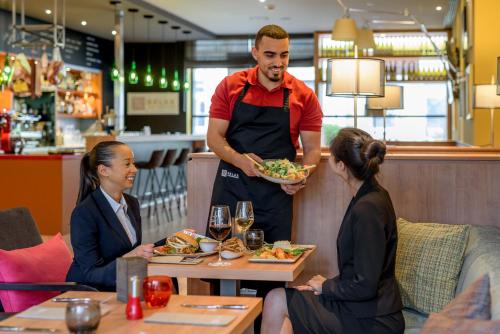 a man holding a plate of food in a restaurant at Mercure Hotel Mannheim am Rathaus in Mannheim