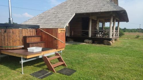 a small hut with a table and a chair in the grass at Lāču namiņš/Bear house in Liepāja