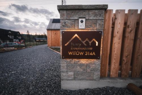 un cartello su un pilastro di pietra vicino a una recinzione di Tatry Zachodnie a Witów