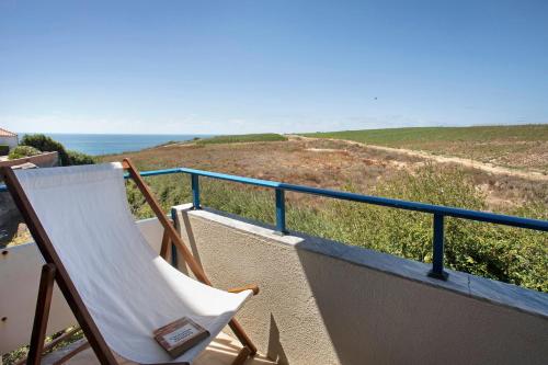 een schommelstoel op een balkon met uitzicht op de oceaan bij Sao Bernardino Beach House in Atouguia da Baleia