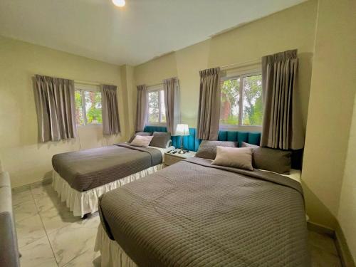 two beds in a room with two windows at Hotel Finca San Nicolas in San Salvador