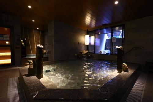 y baño con bañera grande con rocas. en Dormy Inn Express Fujisan Gotemba, en Gotemba