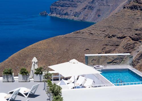 piscina con sedie e ombrellone e oceano di Hotel Thireas a Firà