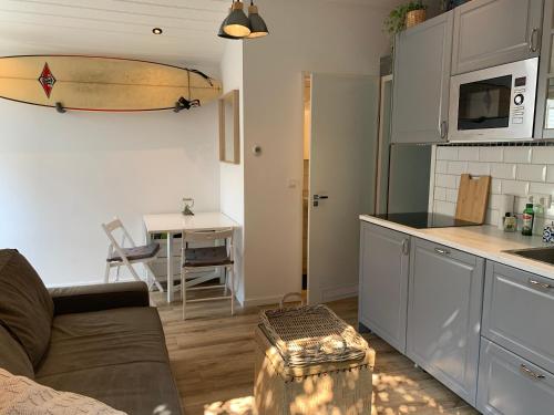 een keuken en een woonkamer met een bank en een surfplank aan de muur bij Tinyhouse Scheveningen beach FREE gated parking in Scheveningen