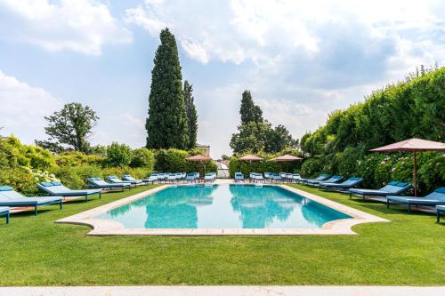 ein großer Pool mit Stühlen und Sonnenschirmen in der Unterkunft Byblos Art Hotel Villa Amistà in San Pietro in Cariano