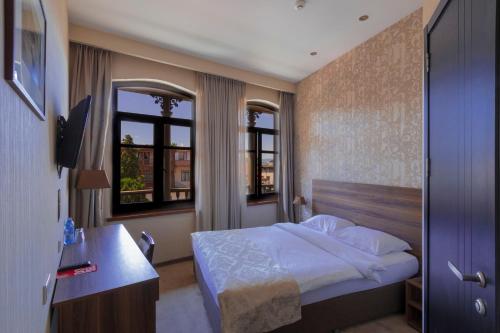 una camera con letto e scrivania e due finestre di Old Meidan Tbilisi By Urban Hotels a Tbilisi City