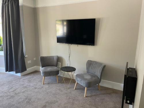 a living room with two chairs and a tv on the wall at Bayside GuestHouse in Bournemouth