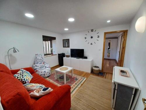 a living room with a red couch and a clock on the wall at Bonito apartamento en Laredo in Laredo