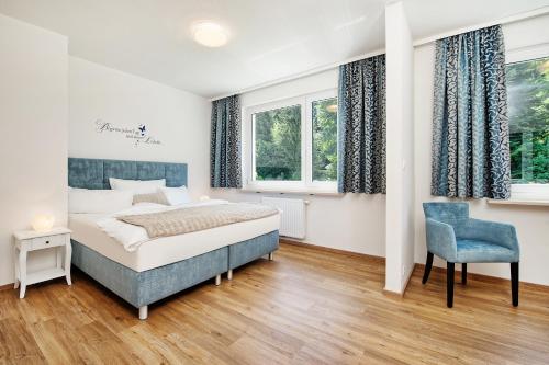 sypialnia z łóżkiem, krzesłem i oknami w obiekcie Appartements Schwarzvilla w mieście Velden am Wörthersee