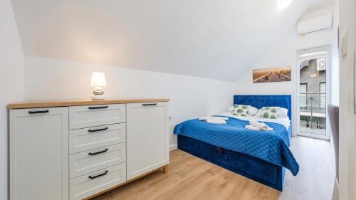 Un pequeño dormitorio con una cama azul y un tocador en Apartamenty Sun & Snow Horizon Park, en Dziwnówek