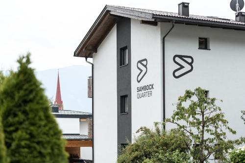 een wit gebouw met een teken dat staat voor synergie verenigd bij Sambock Quarter Pustrabase in Brunico