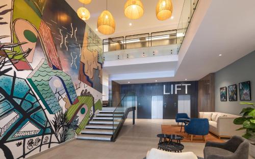 a lobby with a staircase and a large mural at Campanile El Mechtel Tunis in Tunis