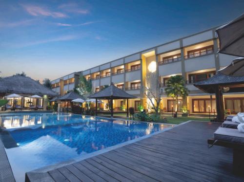 Sima Hotel Kuta Lombok في كوتا لومبوك: فندق فيه مسبح بالليل